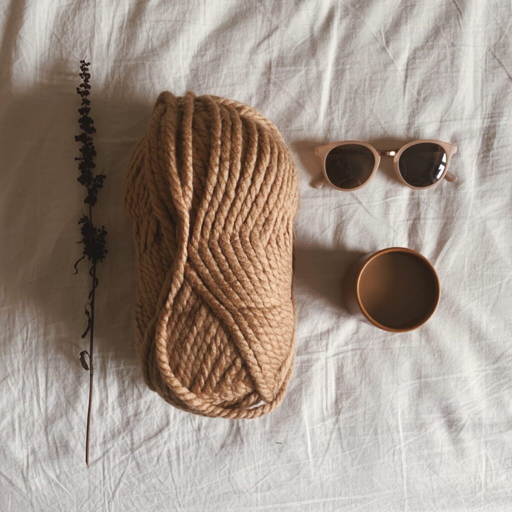 Et nøgle garn på en seng med en kop kaffe og solbriller