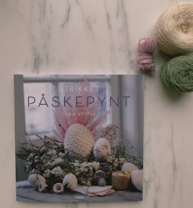 bogen "strikket påskepynt" på et bord med garn til siden