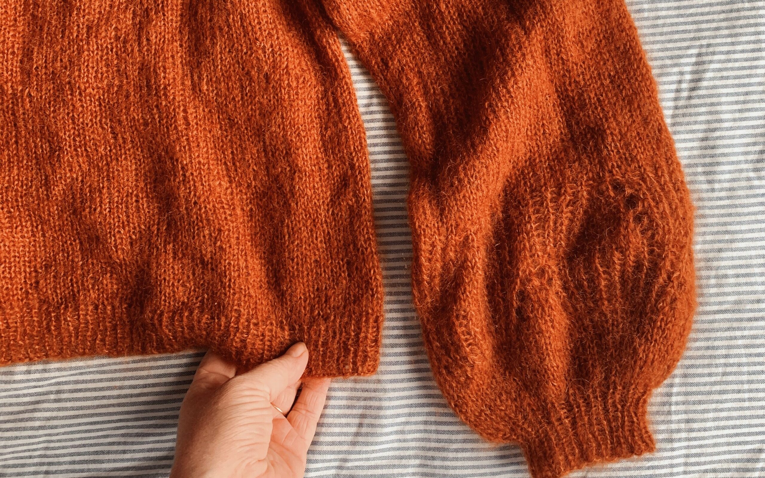 Skibhus sweater af Mette Lundstad liggende på en seng