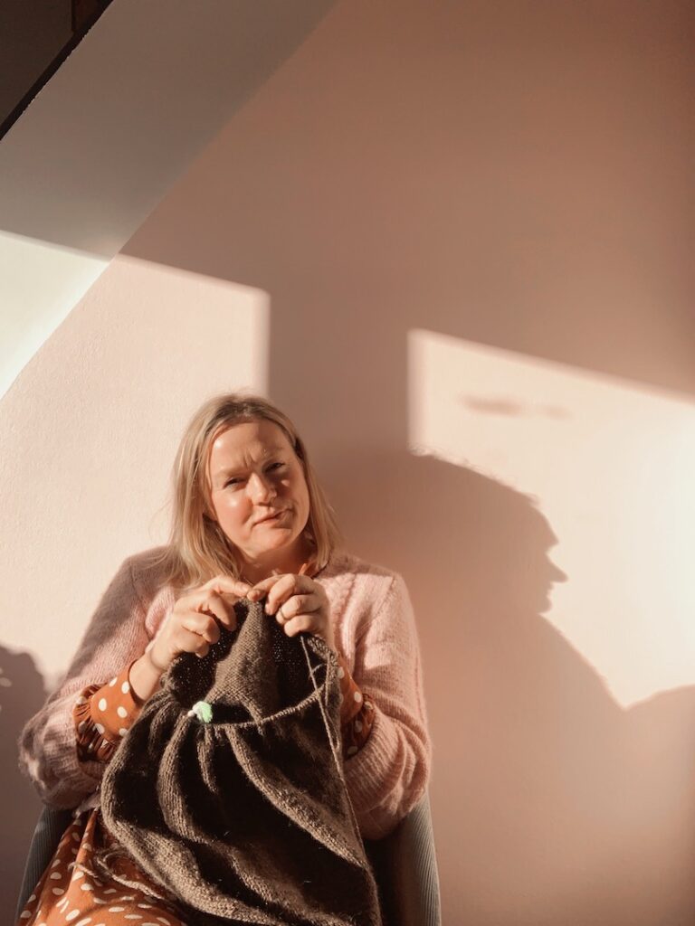 Mette Lundstad der sidder i en sol stråle og strikker